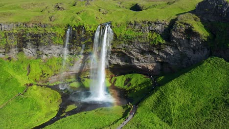 Touristen-Besuchen-Im-Sommer-In-Südisland-Den-Atemberaubenden-Seljalandsfoss-Wasserfall-Mit-Regenbogen