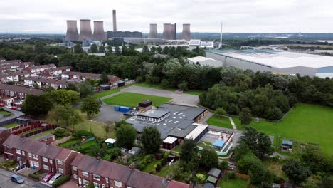 British-industrial-residential-neighbourhood-aerial-view-across-power-station-suburban-houses-and-streets-rising-shot