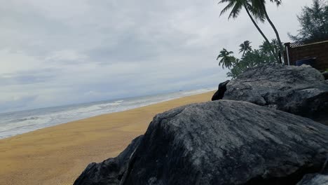 Beach-scenery-during-cloudy-day-with-rocks-and-palm-trees
