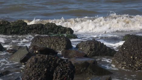 Kleine-Felsen-Am-Strand,-Die-Von-Den-Wellen-Getroffen-Wurden