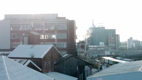 Old-industrial-chemical-warehouse-buildings-aerial-view-factory-steam-smoke-emissions-early-morning-slow-right