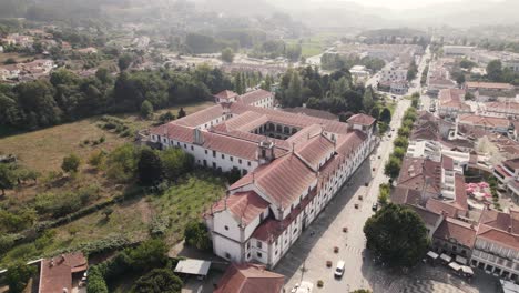 Aerial-pan-above-Abbey-of-Arouca-and-a-straight-road-down-on-Avenida-25-de-Abril,-Portugal