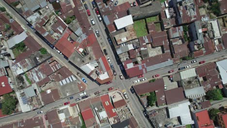 Drone-aerial-footage-of-central-american-urban-city-streets-with-usual-foot-and-car-traffic-in-Quetzaltenango,-Xela,-Guatemala