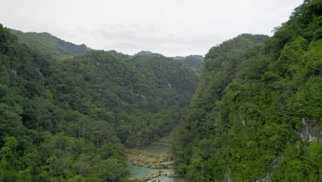 Drohne-Luftaufnahmen-Des-Semuc-Champey-Nationalparks-In-Guatemala,-Umgeben-Von-Hellgrünen-Regenwaldhügeln-Und-Bergen-An-Einem-Bewölkten-Tag