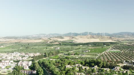 Aerial-view-of-the-Calabrian-hinterland,-olive-fields-and-wind-turbines-in-the-background,-Calabria,-Italy