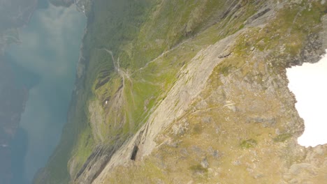 Fpv-flight-downhill-from-mountaintop-in-direction-valley-with-fjord-in-Norway---Overlooking-Odda-City-from-Rossnos-Mountain