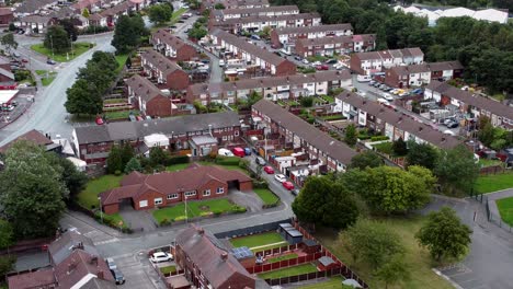 Aerial-view-above-British-neighbourhood-small-town-residential-suburban-property-gardens-and-town-streets-descend-slow