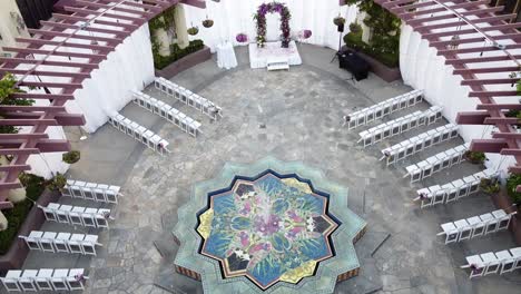 Aerial-top-down-view-of-a-reception-area-of-the-marriage,-wedding-ceremony-under-the-open-sky-with-white-folding-chairs