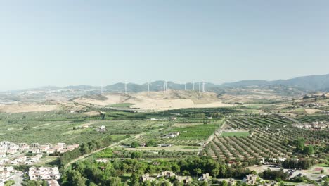Aerial-view-of-the-Calabrian-hinterland,-olive-fields-and-wind-turbines-in-the-background,-Calabria,-Italy