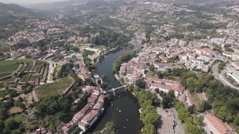 Rooftops-of-Amarante-town-surrounding-Tamega-river,-aerial-ascend-view