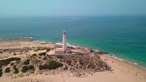 Aerial-View-Of-Beach-And-Historic-Lighthouse-At-The-Headland-Of-Cape-Trafalgar-In-Cadiz,-Spain