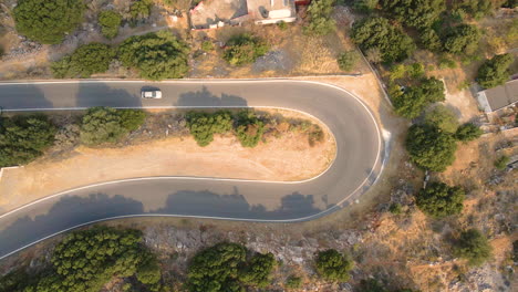 Top-View-Of-White-Car-Driving-Slowly-Through-A-Curved-Road-In-Crete-Island,-Greece