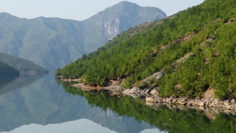 Mountain-lake-in-Albania-with-calm-water-reflecting-high-peaks-and-green-vegetation