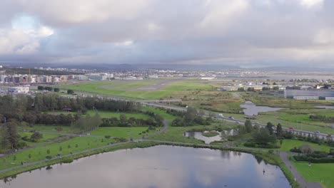 View-of-Reykjavik-airport-in-Iceland,-flying-above-lake-Tjörnin,-aerial