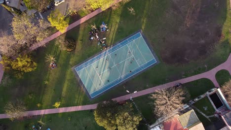 Aerial-top-down-shot-of-many-friends-playing-amateur-volleyball-on-field-in-park