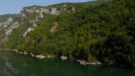 Green-trees-on-mountains-reflecting-on-calm-water-of-Koman-lake-in-Northern-Albania