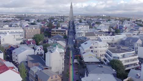Rainbow-road-leading-towards-famous-church-Hallgrimskirkja-in-Reykjavik,-aerial
