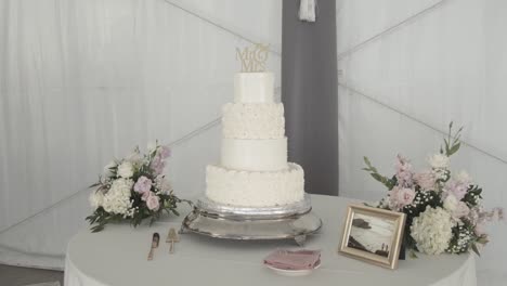 Front-view-of-the-wedding-cake-with-accompanying-flowers,-cutlery-and-photo