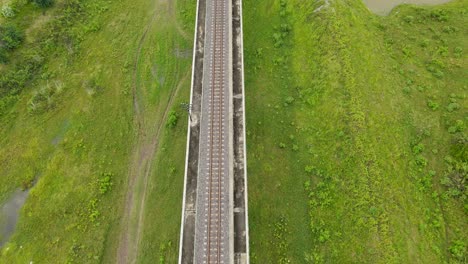 Reverse-aerial-footage-of-an-elevated-railroad,-grassland-both-left-and-right,-Saraburi,-Thailand