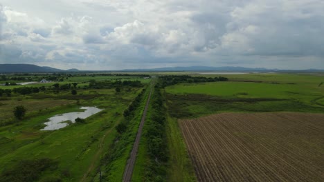 Descending-aerial-footage-revealing-a-gorgeous-horizon,-provincial-railroad,-farmlands,