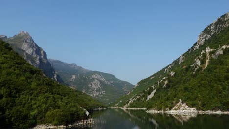 Beautiful-valley-of-Koman-lake-in-Albania,-high-mountain-peaks-reflecting-on-calm-water