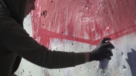 Young-man-painting-graffiti-on-wall.-Slow-motion