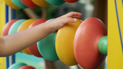 Child's-Hand-Playing-Colorful-Abacus-Toy-Equipment-At-The-Playground