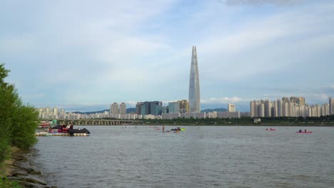 A-leisurely-day-windsurfing-on-the-Han-River-in-Seoul,-South-Korea-with-the-Lotte-World-Tower-on-the-city-skyline
