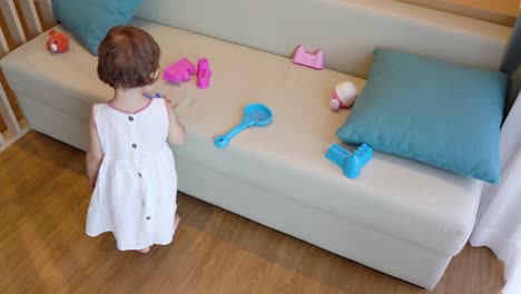 Kluges-Kleines-Mädchen,-Das-Allein-Auf-Einem-Sofa-Zu-Hause-Mit-Spielzeug-Spielt
