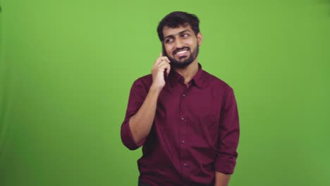 Young-Indian-male-talking-on-phone-with-cheerful-smile,-isolated-on-green-screen