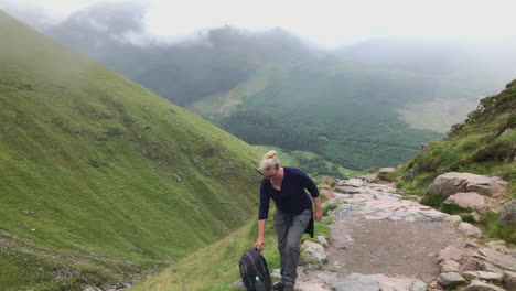 Female-Hiker-With-Heavy-Backpack-Rests-For-A-While-At-Ben-Nevis-Mountain-In-Scotland,-wide-shot