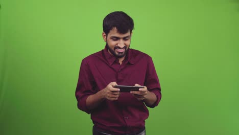 Handsome-man-playing-games-on-smartphone-and-wins,-isolated-on-green-screen