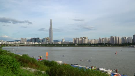 Paddelbootfahren-Und-Windsurfen-Am-Hangang-Fluss-In-Seoul-Mit-Lotte-World-Tower-Und-Jamsil-Bridge-Im-Hintergrund