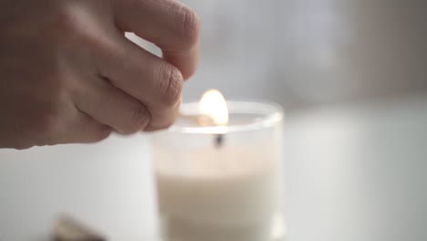Slow-motion-of-hand-lighting-up-white-candle-with-matchstick-inside-home-for-dinner,close-up
