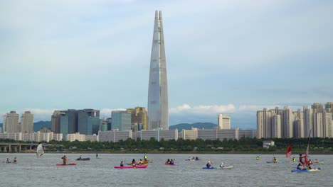 Actividad-De-Deportes-Acuáticos---Kayak,-Windsurf,-Remo---En-El-Río-Han-Con-El-Rascacielos-Lotte-World-Tower-En-Segundo-Plano-En-Seúl,-Corea-Del-Sur