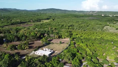 drone-shot-capturing-rural-green-countryside-of-dominican-republic-revealing-large-mountains-in-the-background
