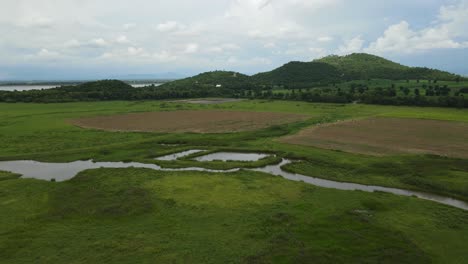 Umgekehrte-Luftaufnahmen-Von-Hügeln-Mit-Bäumen,-Einem-See,-Grasland,-Ackerland-Und-Der-Hochbahn-In-Muak-Klek,-Saraburi,-Thailand