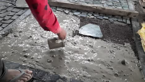 Workers-performing-floor-application-and-pouring-cement-water-on-the-concrete-for-fixing-small-stones