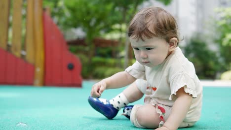 Während-Mama-Oder-Papa-Seifenblasen-Machen,-Ist-Baby-Daran-Interessiert,-Steine-Auf-Dem-Spielplatz-Aufzuheben