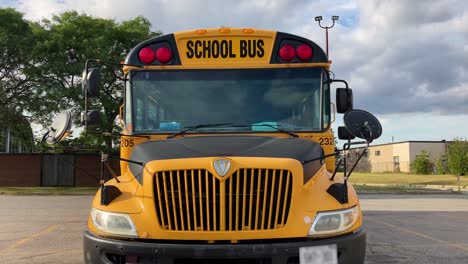 School-bus-close-up-dolly-back-revealing-front-mirrors-of-bus-parked-at-school