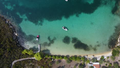 Overhead-drone-clip-of-a-small-tropical-island-bay-with-crystal-blue-water-and-luxurious-boats-in-the-area-of-Vourvourou,-in-Northern-Greecem-Halkidiki-in-4K