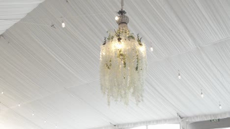 Close-up-of-chandeliers-decorated-with-white-flowers-pendants-in-a-wedding-venue