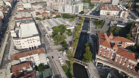 High-angle-view-of-Aveiro-cityscape-and-majestic-canal-with-canoes,-aerial-orbit-view