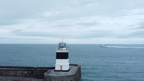 Holyhead-breakwater-lighthouse-longest-concrete-coastal-sea-protection-landmark-aerial-view-ferry-passing-horizon