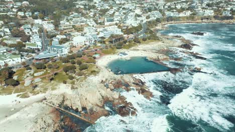 Drone-shot-rough-waves-hitting-rocks-on-city-shoreline