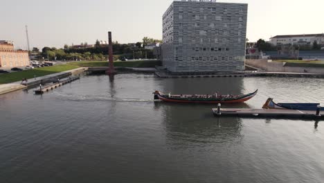 Low-level-aerial-shot-following-the-moving-moliceiro-boat-toward-the-narrow-water-canal-at-Aveiro-city