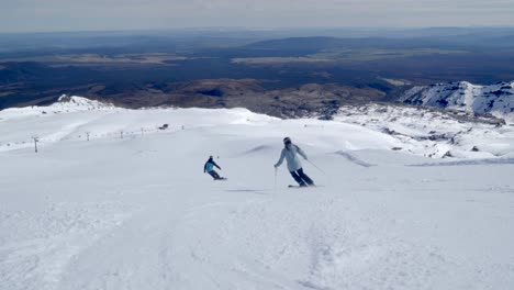 Skier-and-snowboarder-kids-take-off-downhill-alpine-piste-on-Mount-Ruapehu
