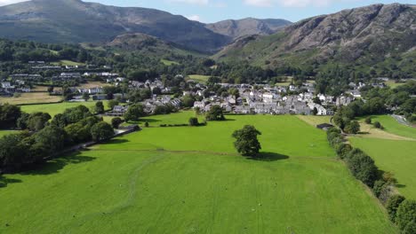 Coniston-Village-Drone-view-over-fields-Lake-District-Cumbria-UK-aerial-footage-4K