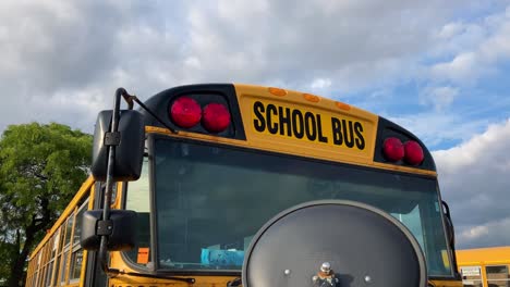 School-bus-close-up-circle-left-showing-red-lights-and-mirrors-while-parked
