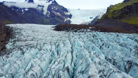 Drone-Flying-Over-Svinafellsjokull-Glacier-With-Deep-Cracks-On-Blueish-Ice-With-Black-Ash-Veins-In-Iceland